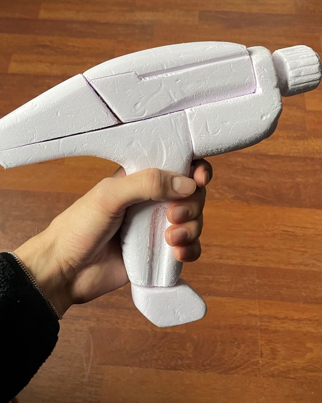 White foam model of the tool held in a hand